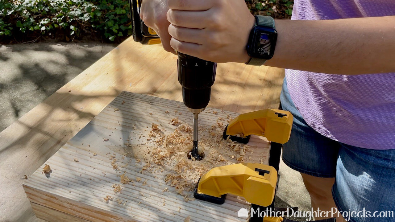 Using a DeWalt drill fitted with a spade bit to cut the holes for the pipe.