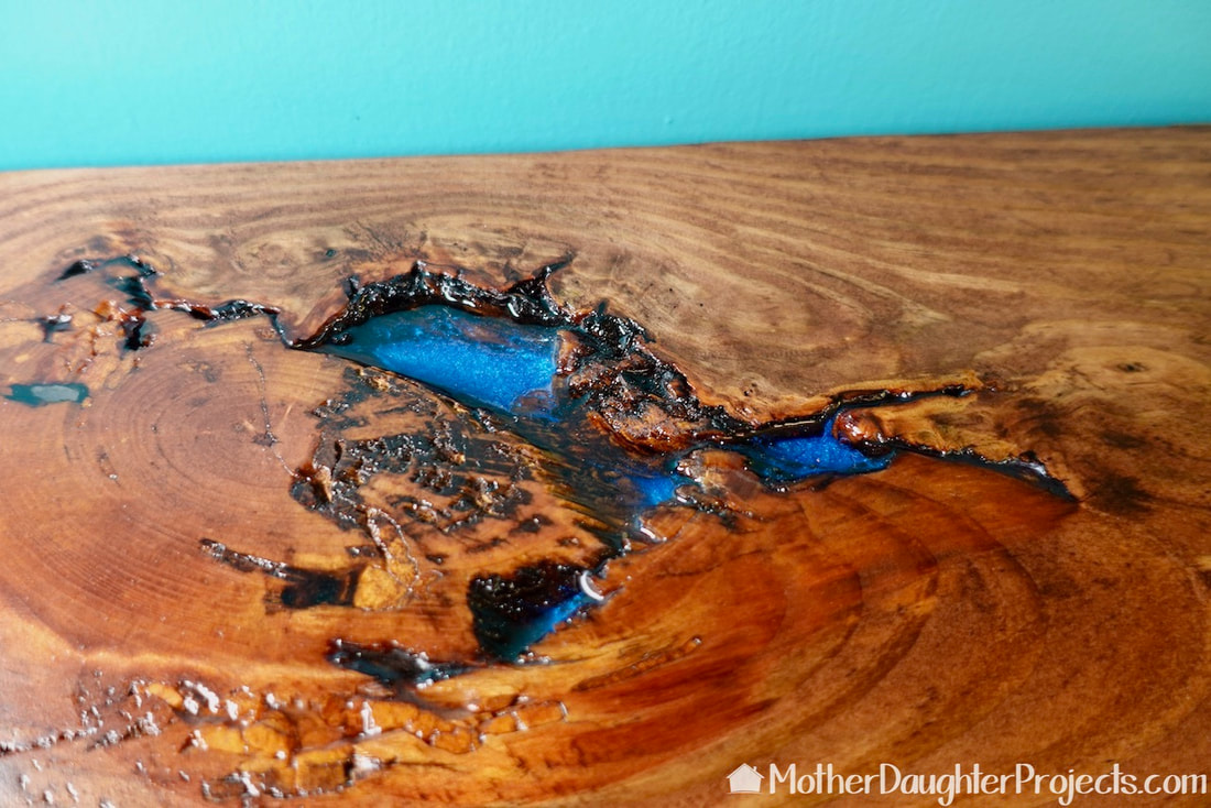 Close up picture of the Totalboat epoxy in the knotholes on the faux live edge table. 