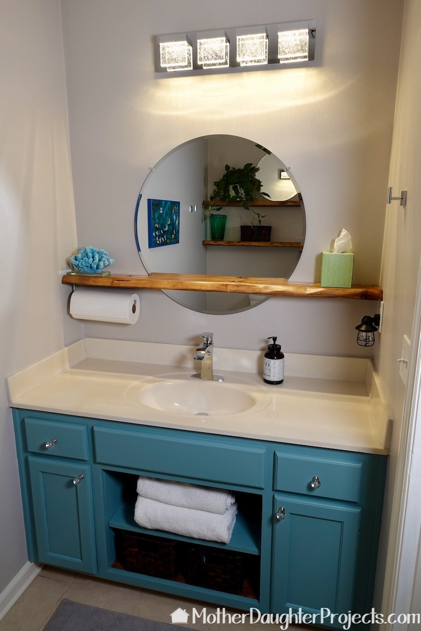 A finished look at the existing vanity with the center opened up with floating round mirror on a floating shelf. 
