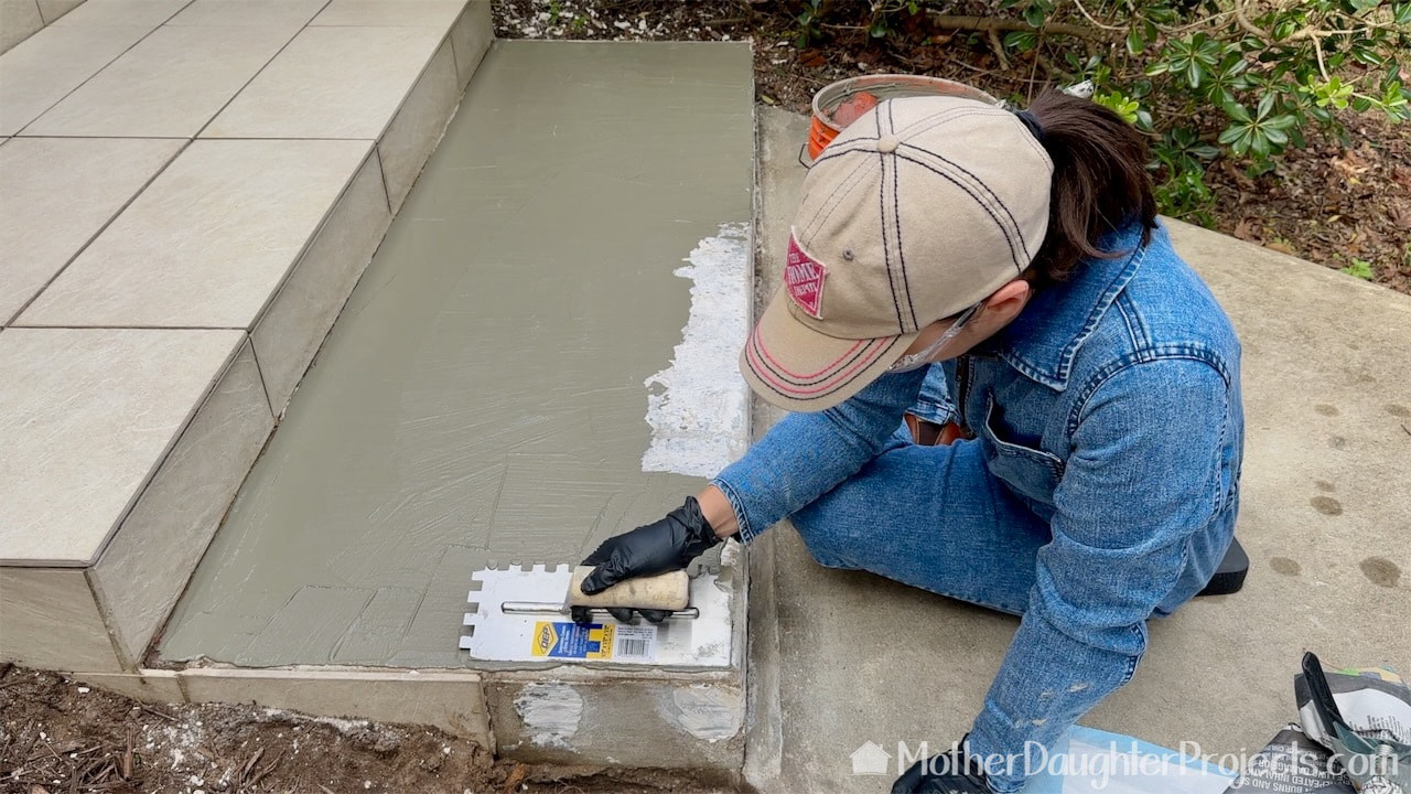 Putting on the mortar in a skim coat prior to laying the tile. 