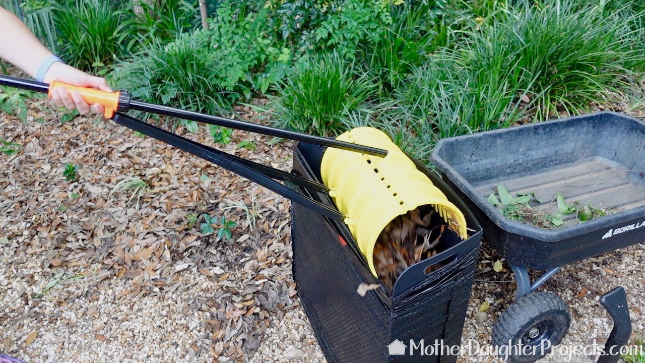 Use the claw action to scoop up the leaves and empty them into the open garbage bag.