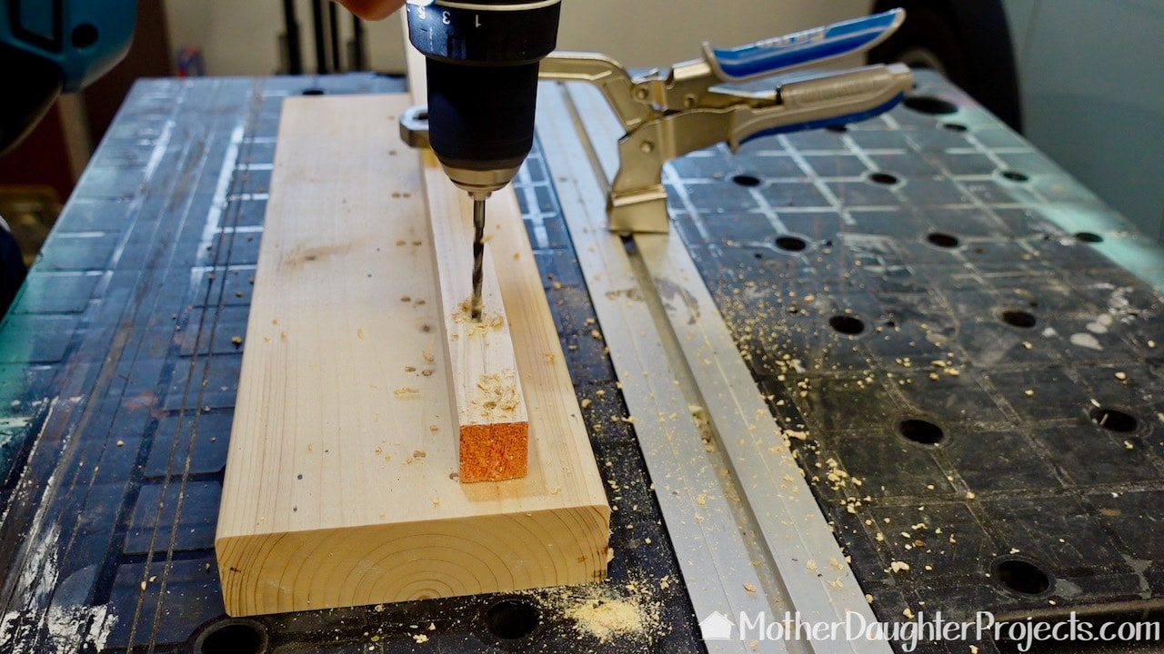 Drilling holes in the wood dowel that will hold the metal rods on which the dog bandanas will be stores. 