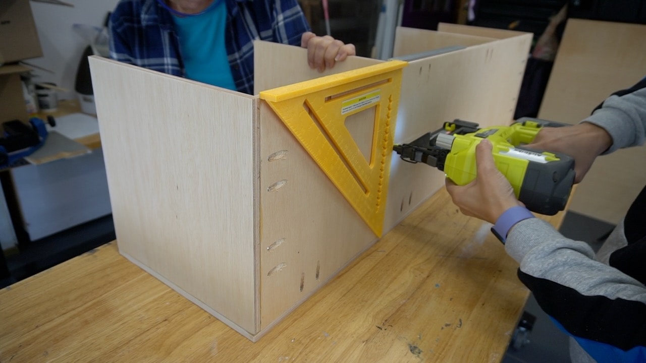 Using a Ryobi brad nailer to assemble parts of thee bathroom cabinet.