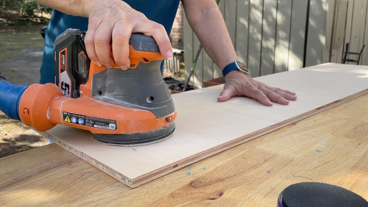 Using a Ridgid battery powered sander to clean up the plywood for the wall-hung bathroom cabinet.