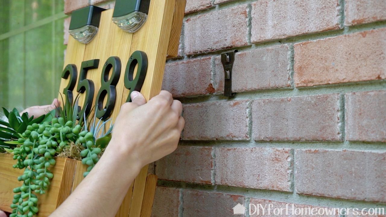 Hanging the modern address sign on the brick clips.