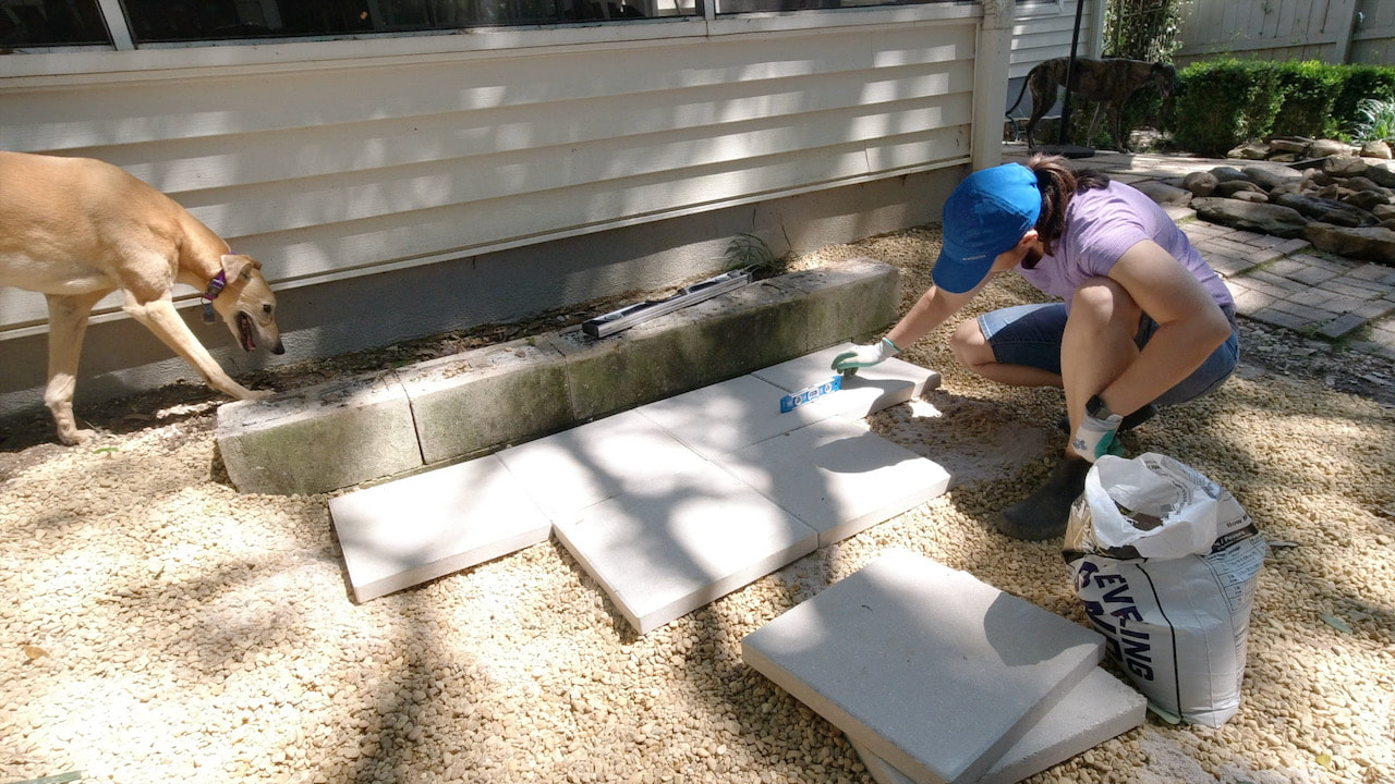 Using a level and leveling sand to place the concrete stepping stone pavers.