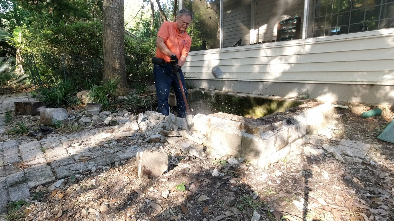 Using a splitting maul to break up the concrete.