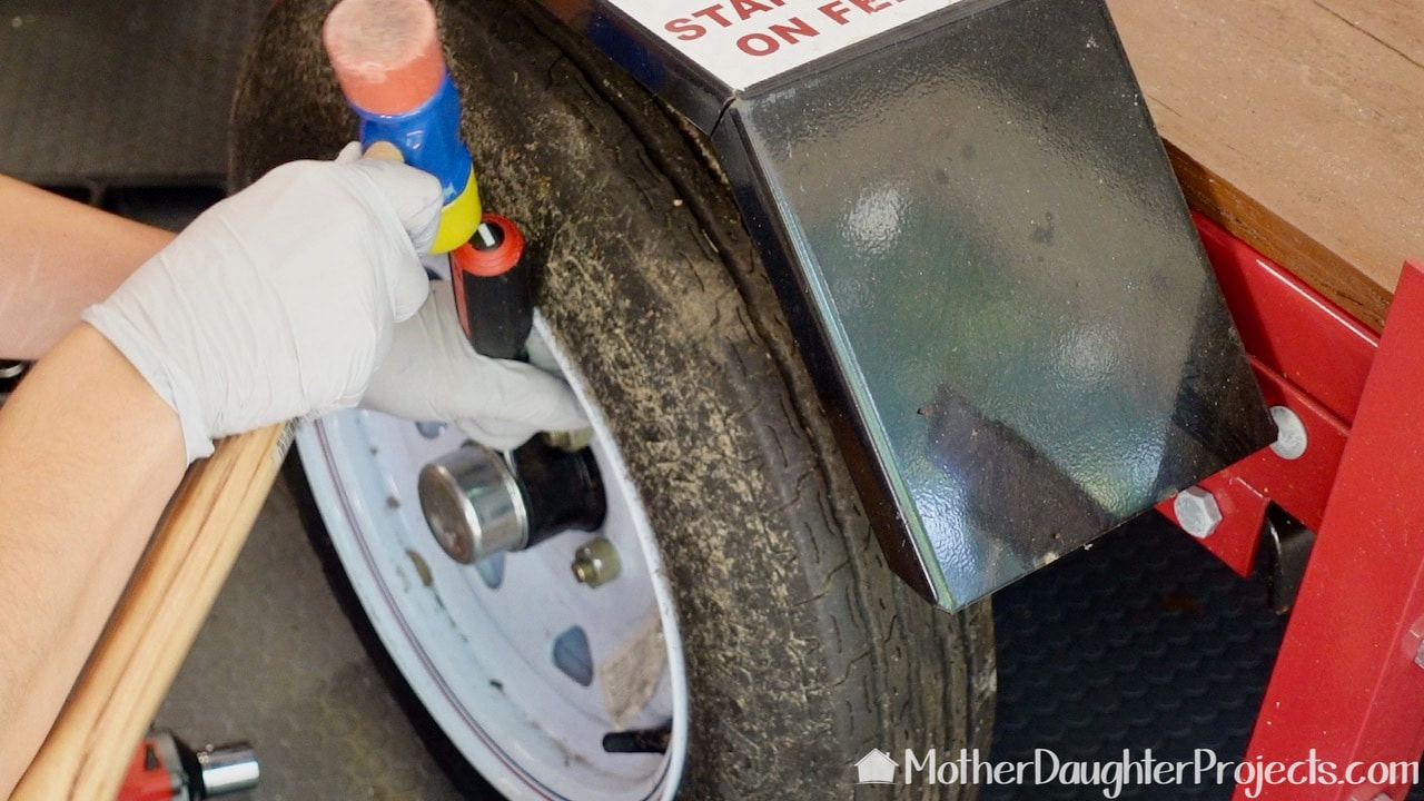 The first step in repacking the bearings on a Harbor Freight trailer is to remove the wheel dust cap.