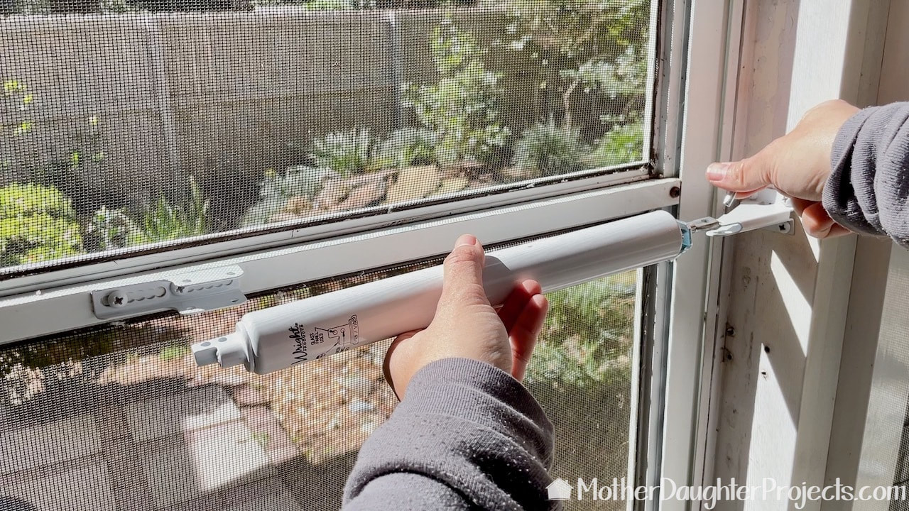The last step in replacing the pneumatic screen door closer is to secure it to the hinges with pins.