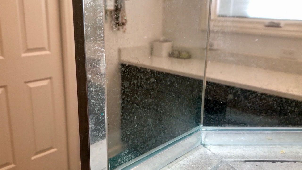 Before shot of the water spots on the glass and metal shower surround. 