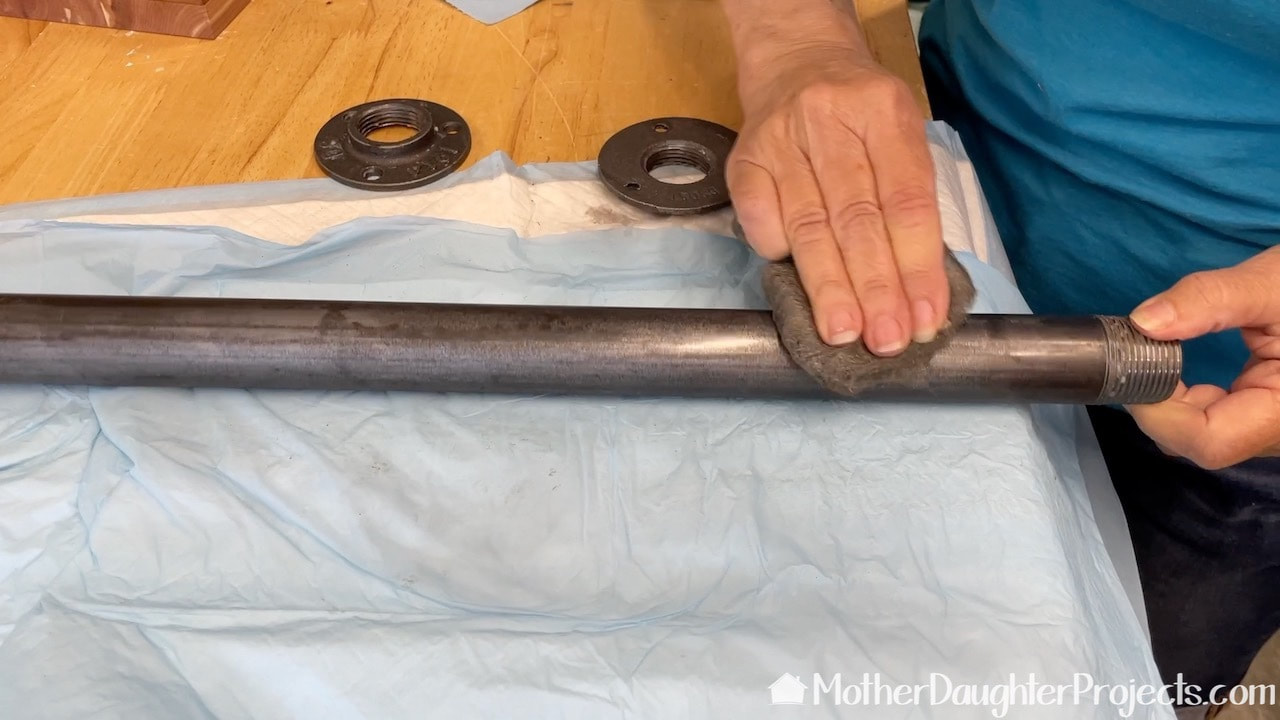 Buffing the wax on the metal pipe with 0000 steel wool.