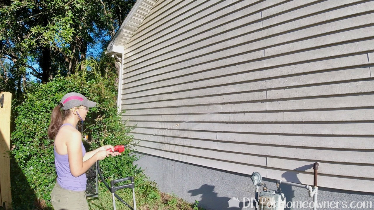Spraying the siding with Wet and Forget in the Milwaukee battery powered tank garden sprayer.